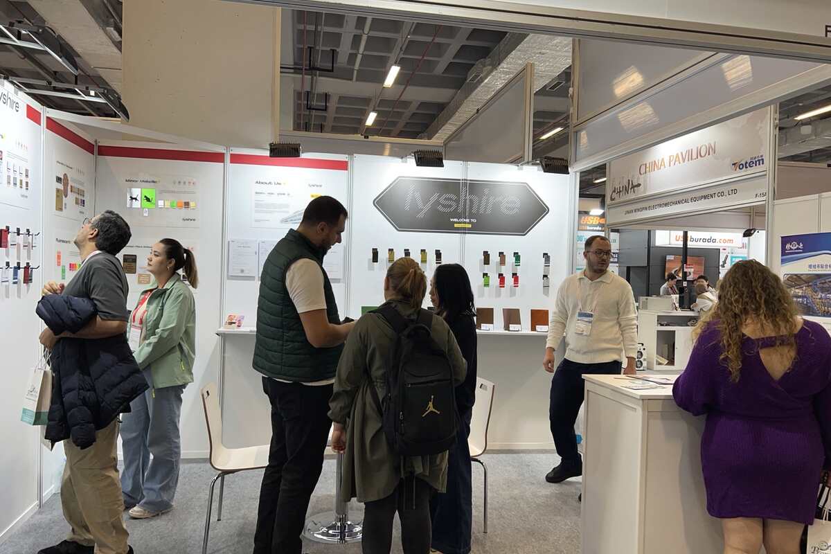 Visitors examining LYSHIRE engraving sheets at the busy F-10C booth during SIGN Istanbul 2025
